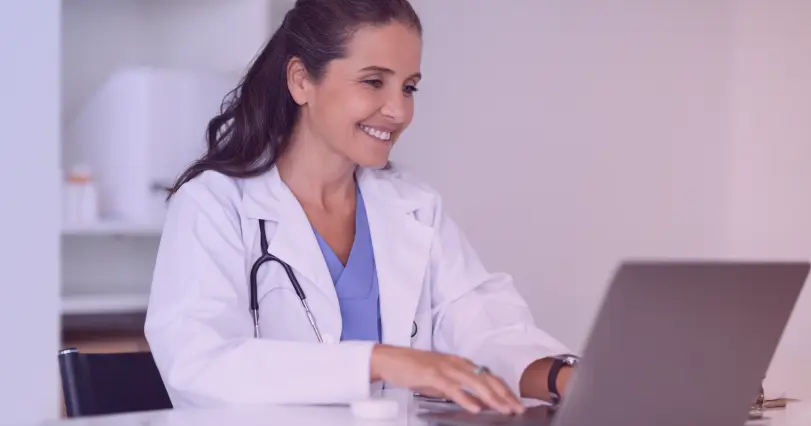 doctor using a laptop and smiling
