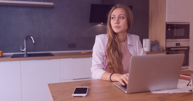 Woman using a laptop while sitting at a dining room table